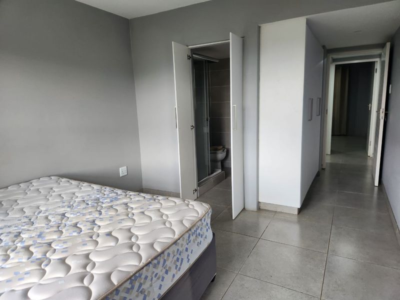 A bedroom featuring tiled flooring, built-in cupboards, and direct access to an en-suite bathroom.