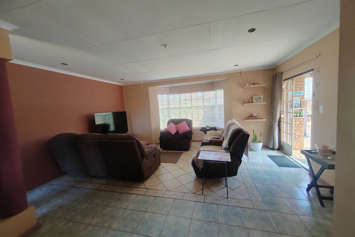 Spacious living room featuring tiled flooring, recessed ceiling lighting, and large windows providing natural light with direct access to the outdoor patio area.