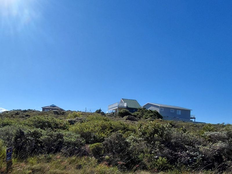 A view of an elevated residential plot featuring natural vegetation and a sloped landscape, suitable for development.