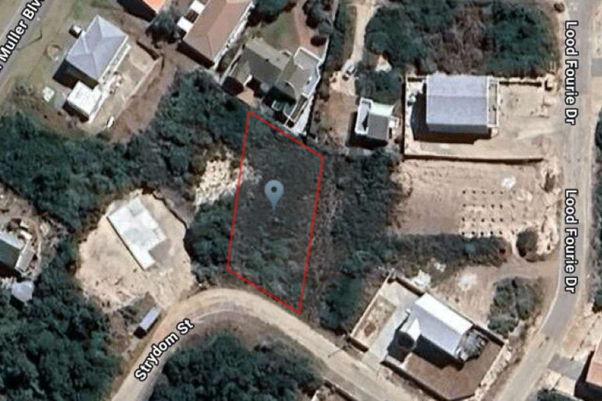 Aerial view of a vacant residential plot highlighted in red, situated within a developed neighborhood with surrounding street access.