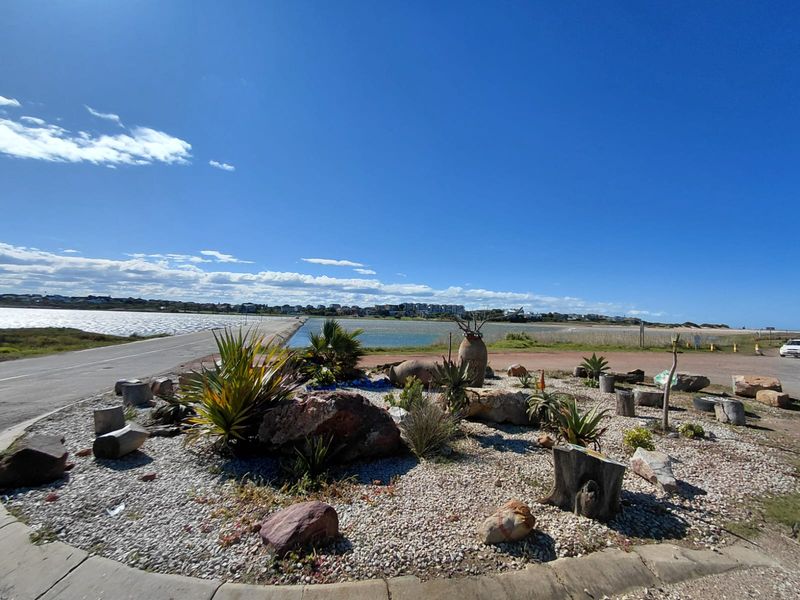 A scenic view of the coastal landscape featuring a landscaped garden area with gravel, natural rocks, and native plants overlooking the water.