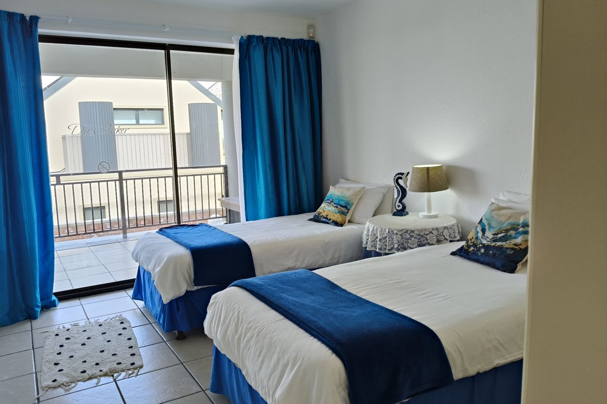 A bedroom featuring tiled flooring and large sliding glass doors that open onto a private balcony.
