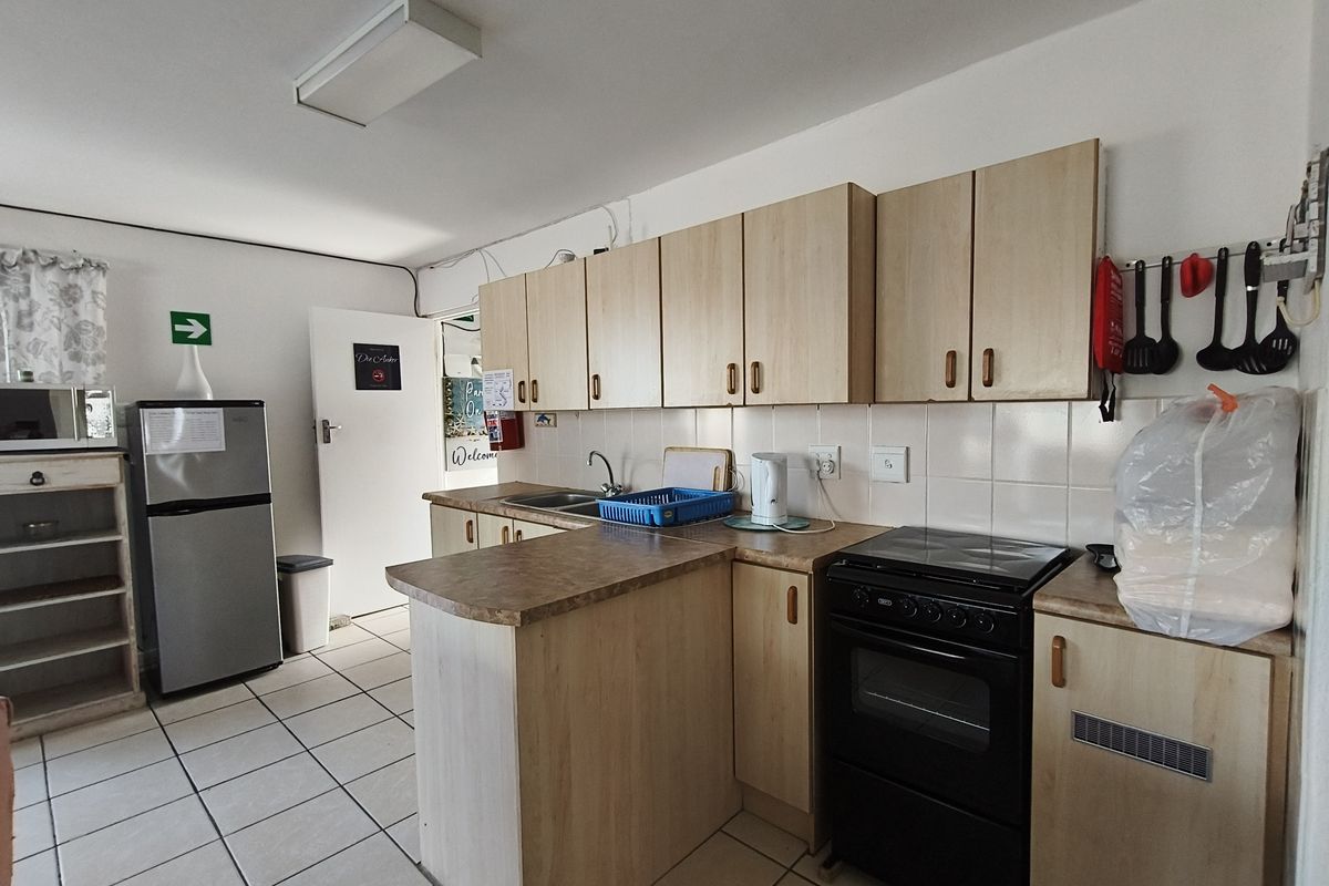Functional kitchen featuring light wood-finish cabinetry, tiled backsplash, laminate countertops, and a freestanding electric stove.