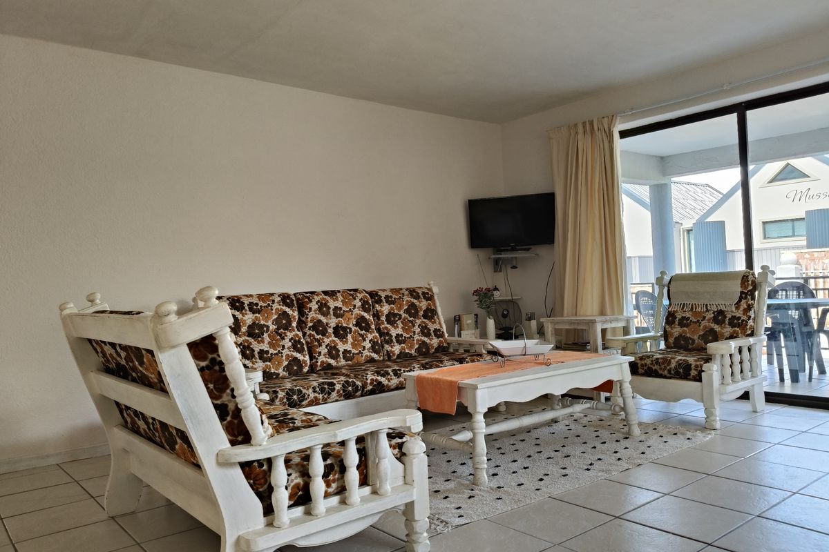 A living room featuring tiled flooring and large sliding glass doors that provide access to an outdoor patio area.