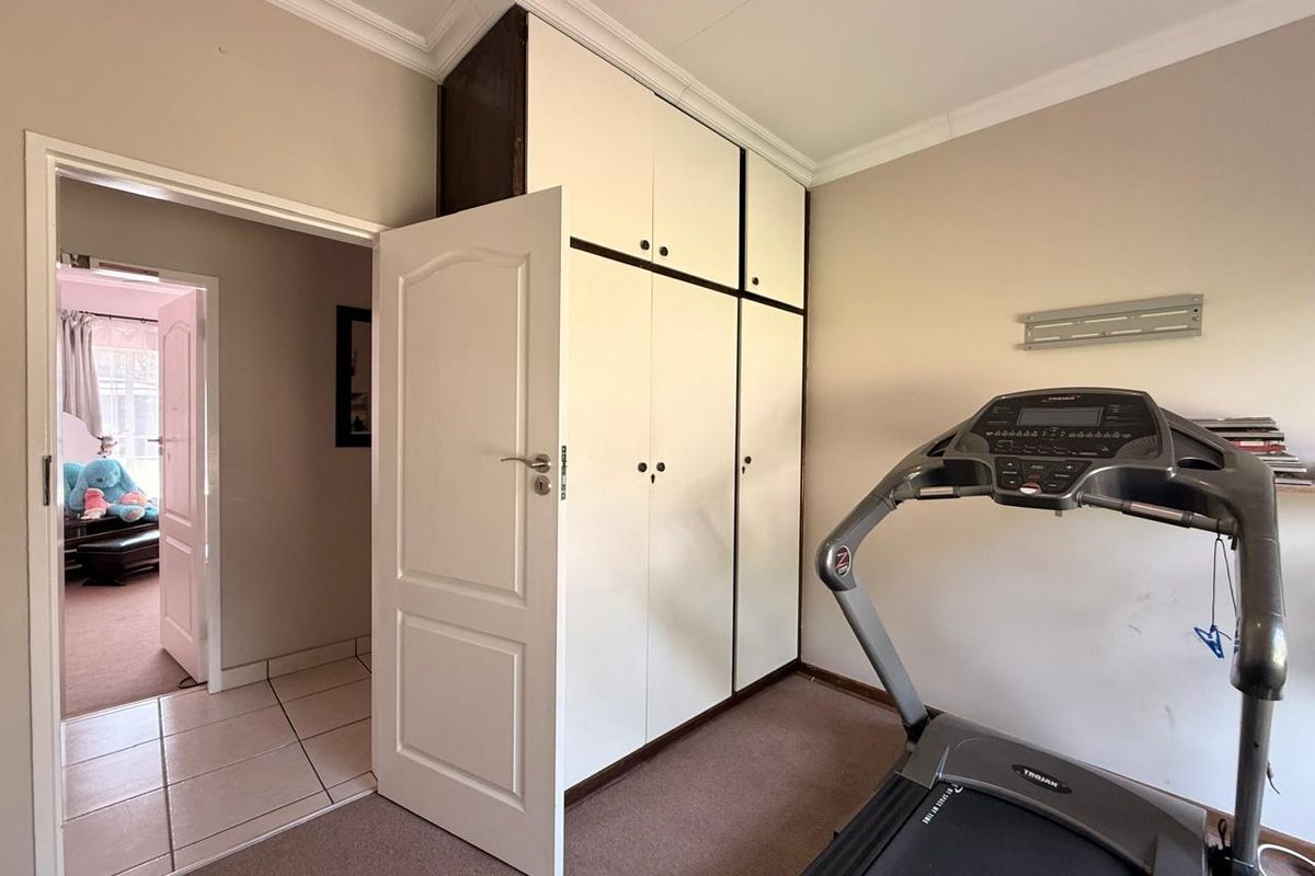 A bedroom featuring built-in floor-to-ceiling cabinetry, crown molding, and carpeted flooring, with an adjacent hallway view.