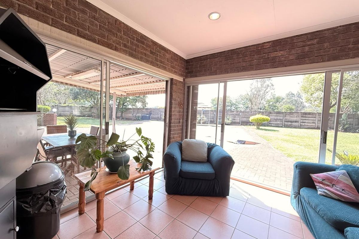Sun-filled living area featuring exposed brick walls, tiled flooring, and large sliding glass doors providing seamless access to the outdoor patio and garden.