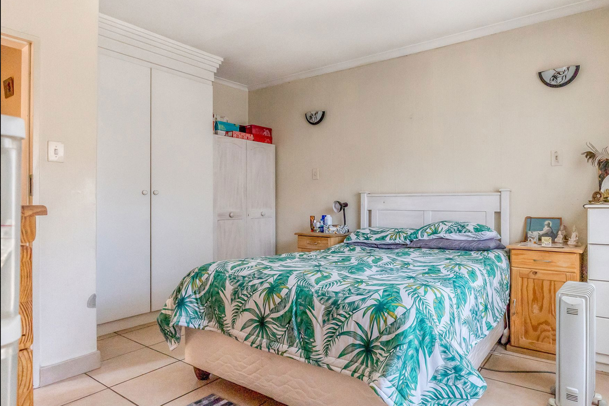 A functional bedroom featuring tiled flooring, built-in wardrobe storage, and wall-mounted lighting fixtures.