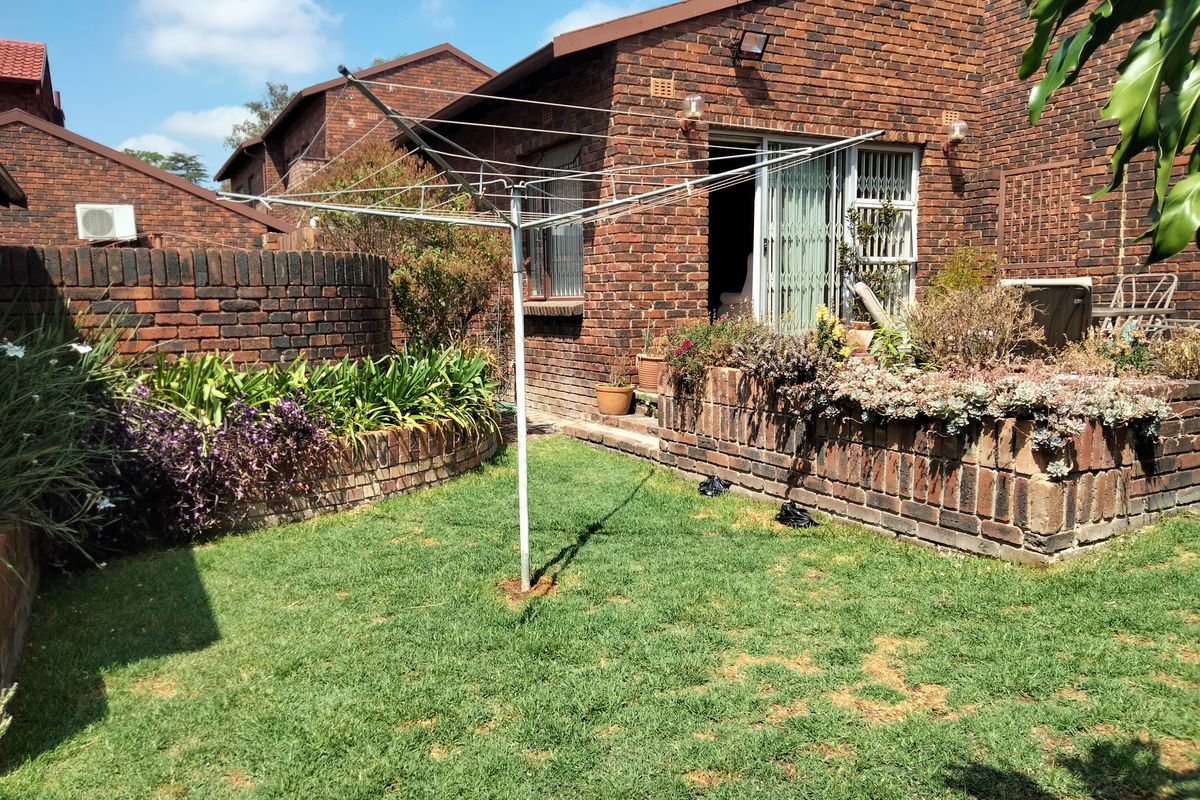 Rear garden area featuring a lawn, raised brick planter beds, and a sliding door entrance to the townhouse.