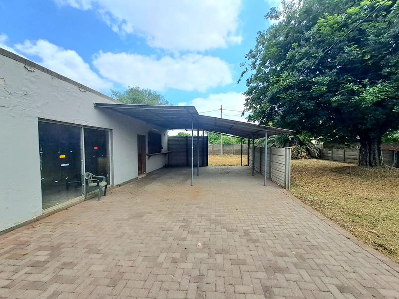 Spacious paved outdoor patio area featuring a metal roof structure, providing a versatile space for outdoor living and entertaining.
