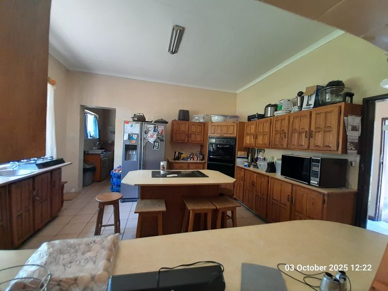 Spacious kitchen featuring traditional wooden cabinetry, a central island with integrated cooktop, and an adjoining scullery area.