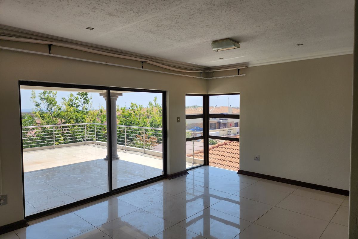 Bright living area featuring large sliding glass doors that open onto a spacious tiled balcony with neighborhood views.