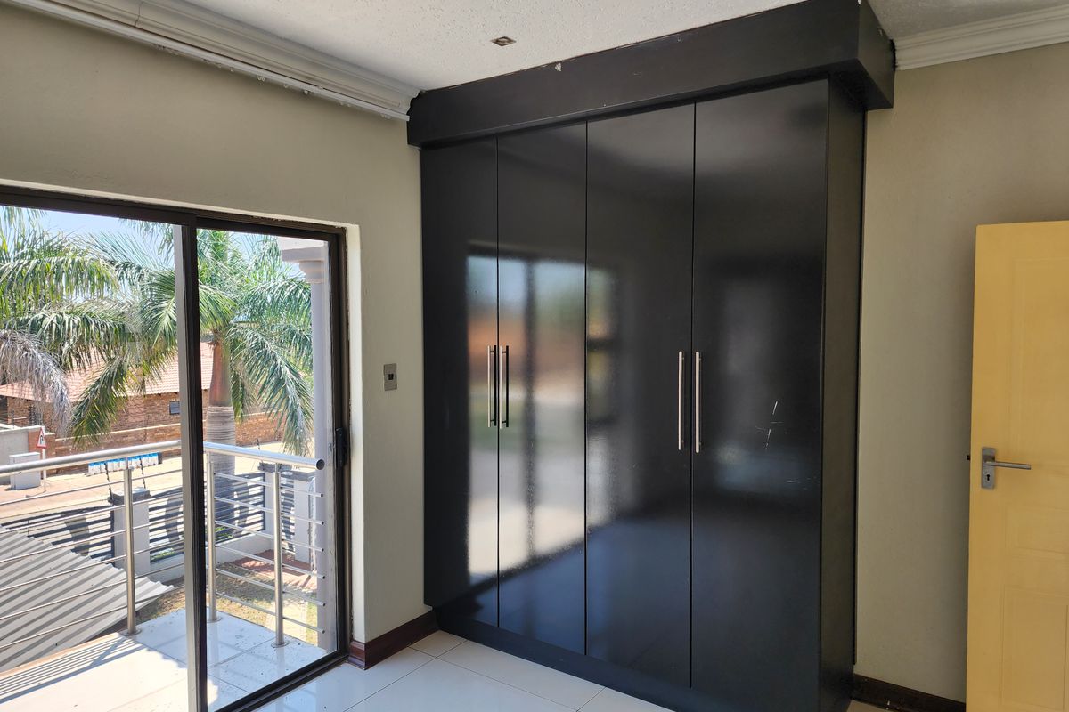 Bedroom featuring built-in floor-to-ceiling black cabinetry and sliding glass doors opening onto a balcony.
