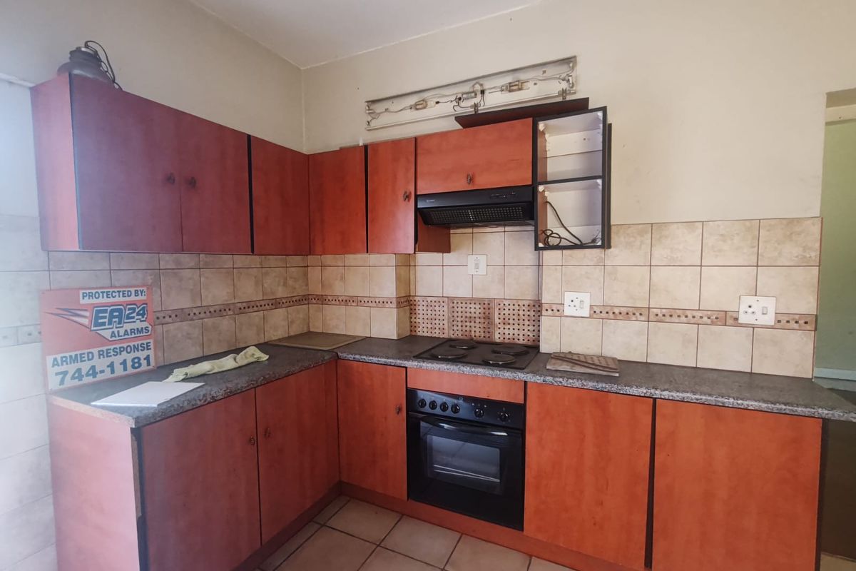 A functional kitchen featuring wood-look cabinetry, tiled splashbacks, a built-in oven, and an extractor fan.