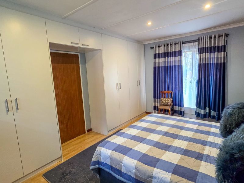A well-maintained bedroom featuring extensive built-in cupboards, laminate flooring, and recessed ceiling lighting.
