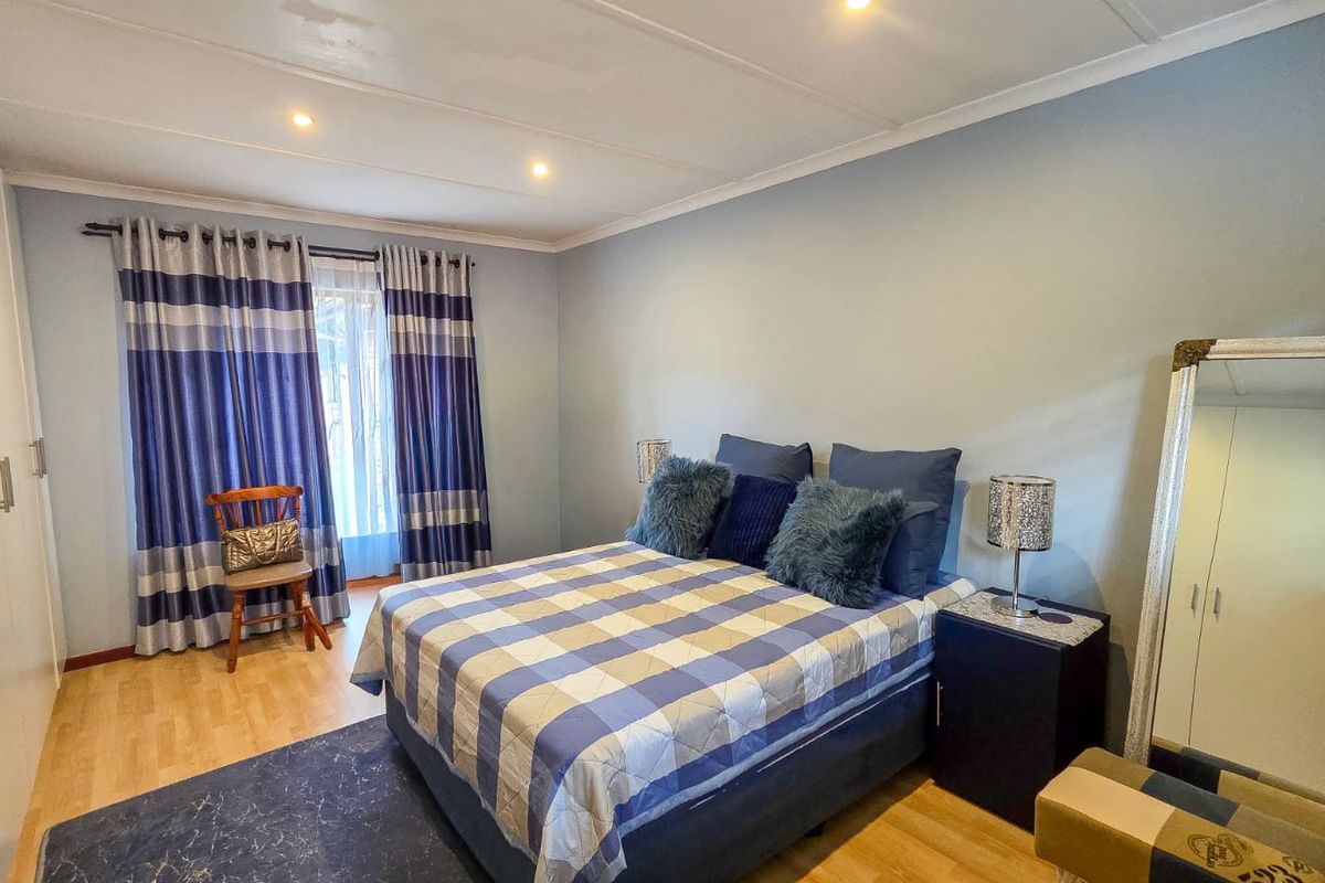 A well-lit bedroom featuring laminate flooring, built-in cupboards, and recessed ceiling lighting, offering a comfortable and functional living space.