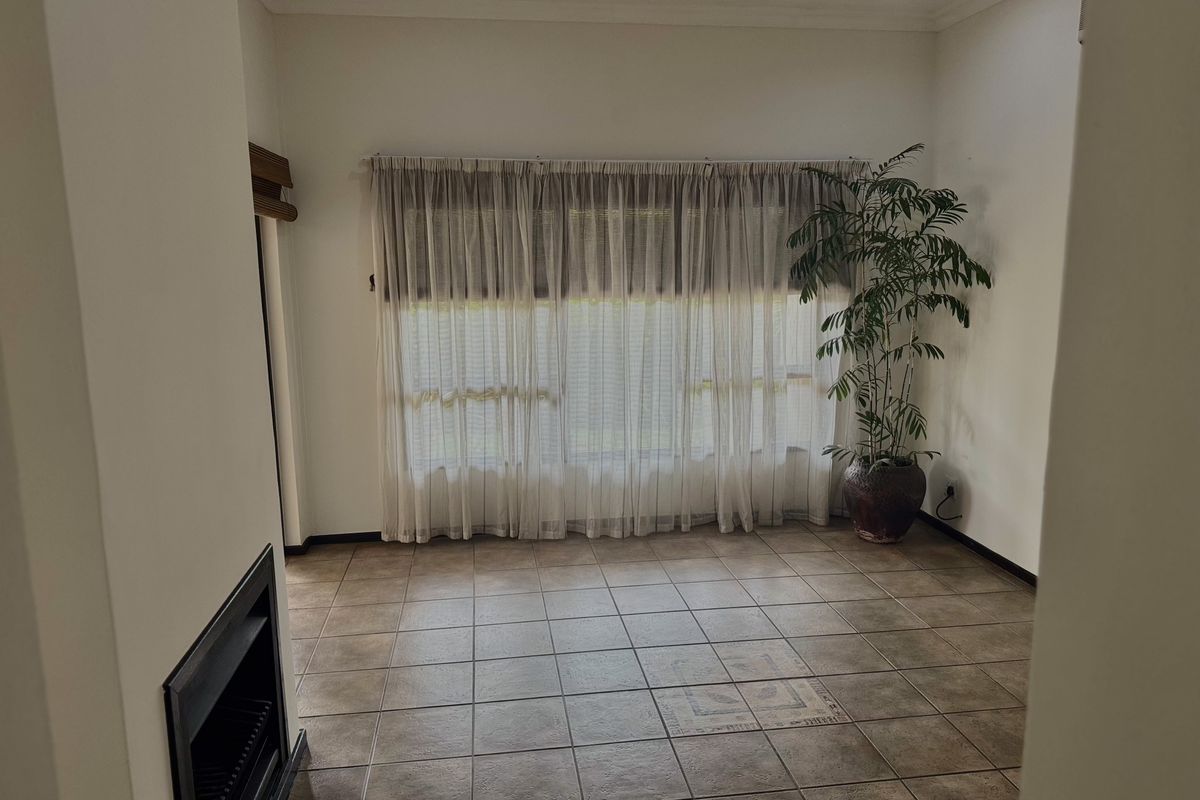 A living room featuring tiled flooring, a built-in fireplace, and large windows with sheer curtains.