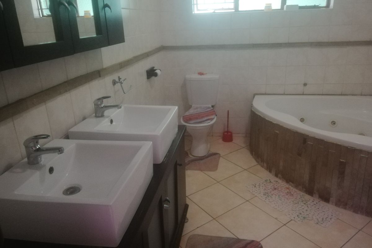 A bathroom featuring a double vanity with vessel sinks, a corner jetted bathtub, and tiled flooring.