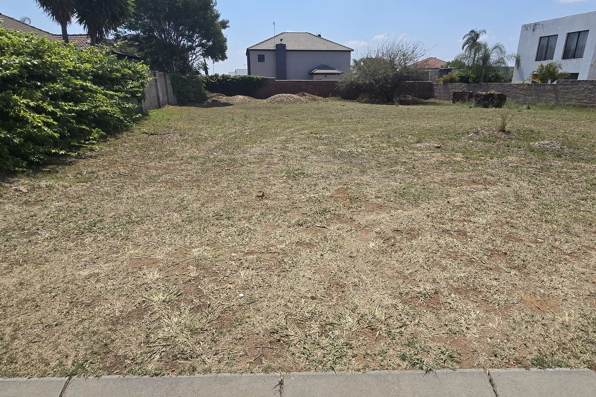 A vacant residential plot featuring a level grassed area enclosed by perimeter boundary walls, offering a clear space for future development.