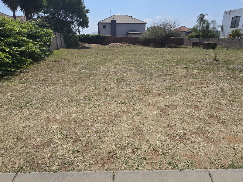 A vacant residential plot featuring a level grassed area enclosed by perimeter boundary walls, offering a clear space for future development.