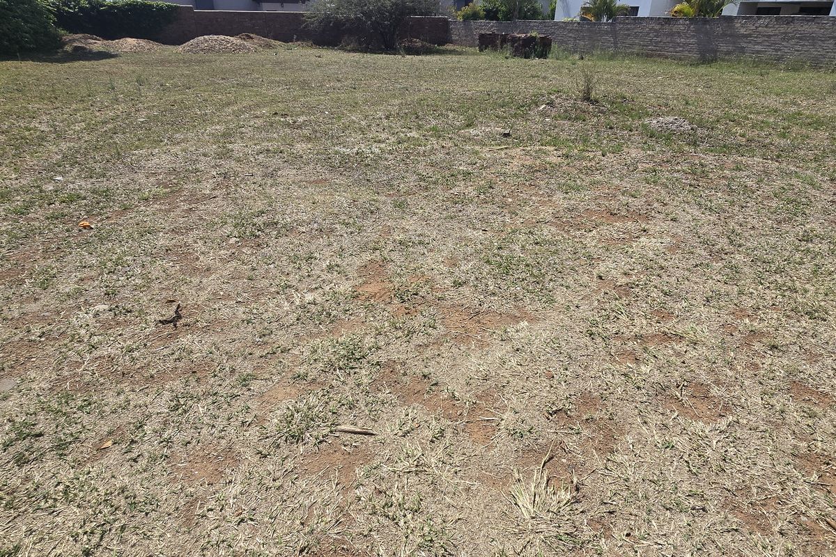 A vacant residential plot featuring level ground, perimeter boundary walls, and established grass coverage, ready for development.
