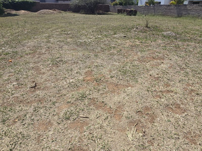 A vacant residential plot featuring level ground, perimeter boundary walls, and established grass coverage, ready for development.