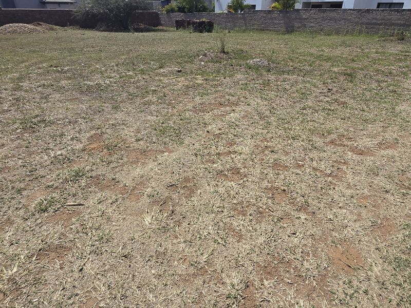 A vacant residential plot featuring level ground, perimeter boundary walls, and established grass coverage, ready for development.