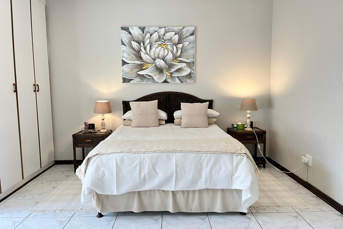 A well-maintained bedroom featuring built-in floor-to-ceiling wardrobes and light-colored tiled flooring.