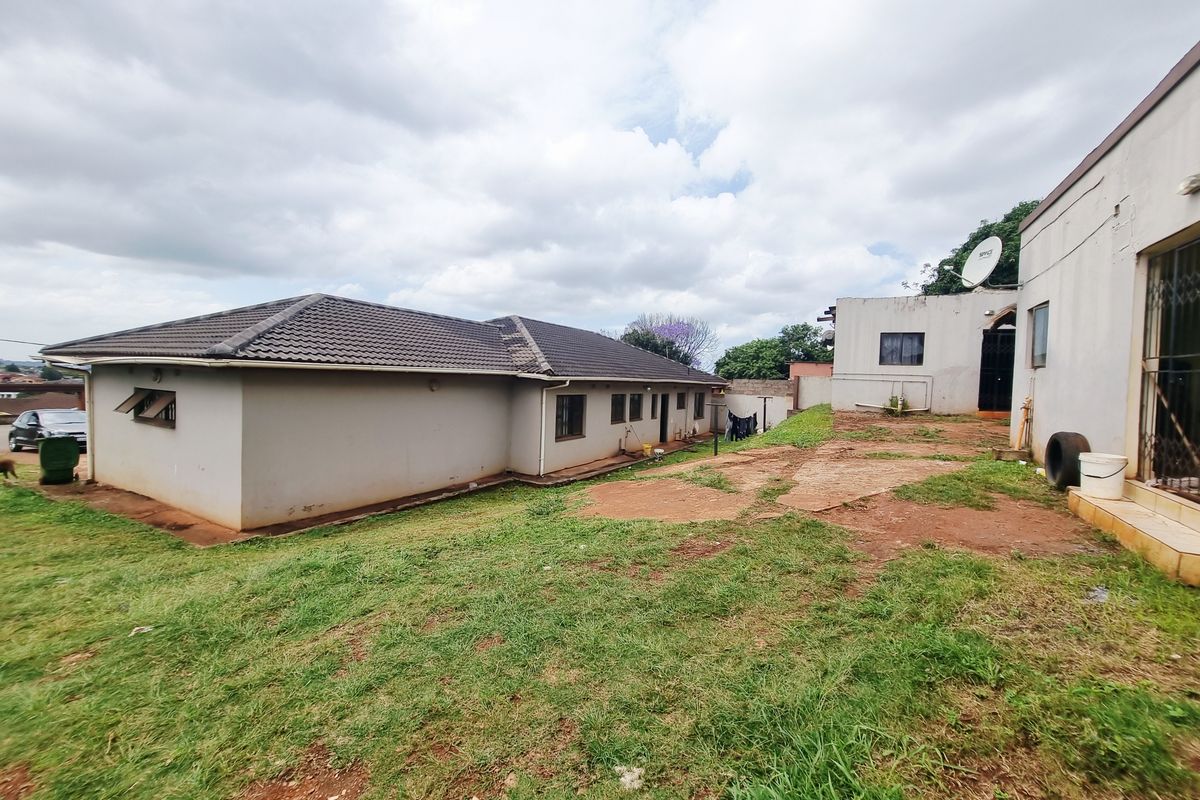 A view of the rear exterior of the property, featuring a large, unlandscaped yard area and the back facade of the house.