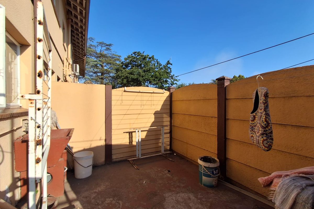 A private rear courtyard area featuring concrete flooring and enclosed by painted boundary walls, suitable for utility or outdoor storage use.