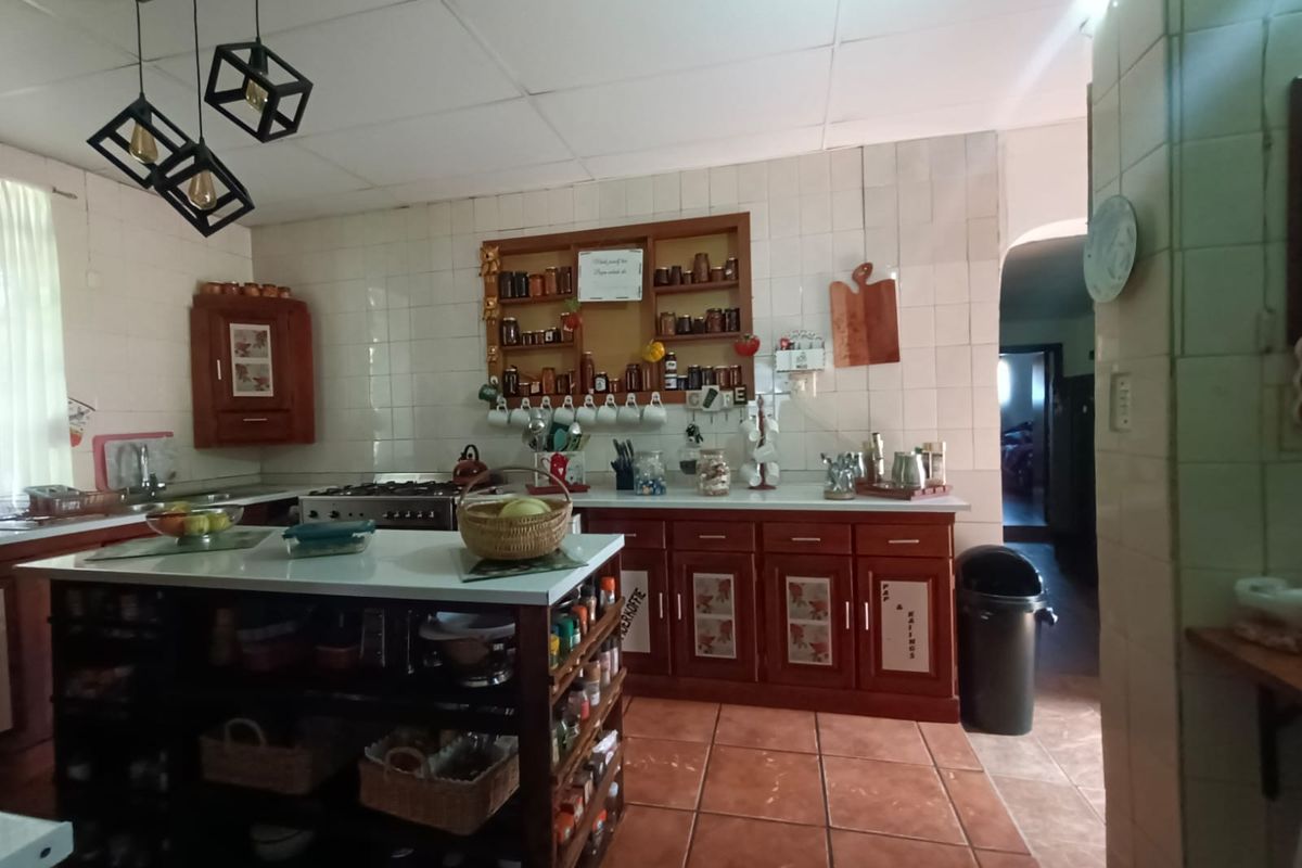 A functional kitchen featuring wooden cabinetry, a central island, tiled backsplash, and modern pendant lighting, offering a traditional farm-style aesthetic.