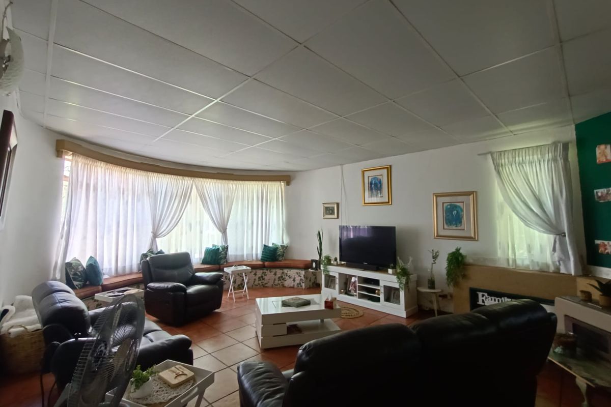 Spacious living room featuring a large curved window with built-in seating, tiled flooring, and a fireplace, offering a comfortable and functional living space.