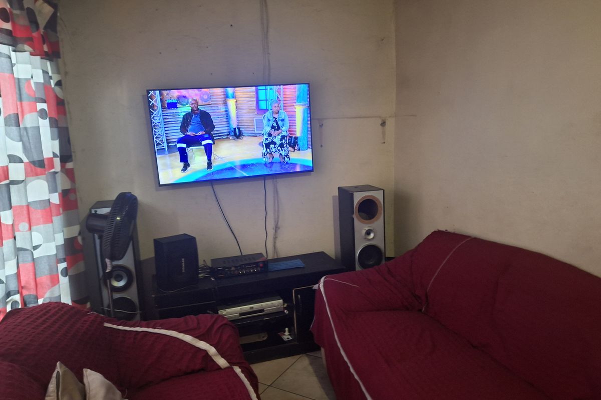 A living room area featuring tiled flooring and wall-mounted television setup.