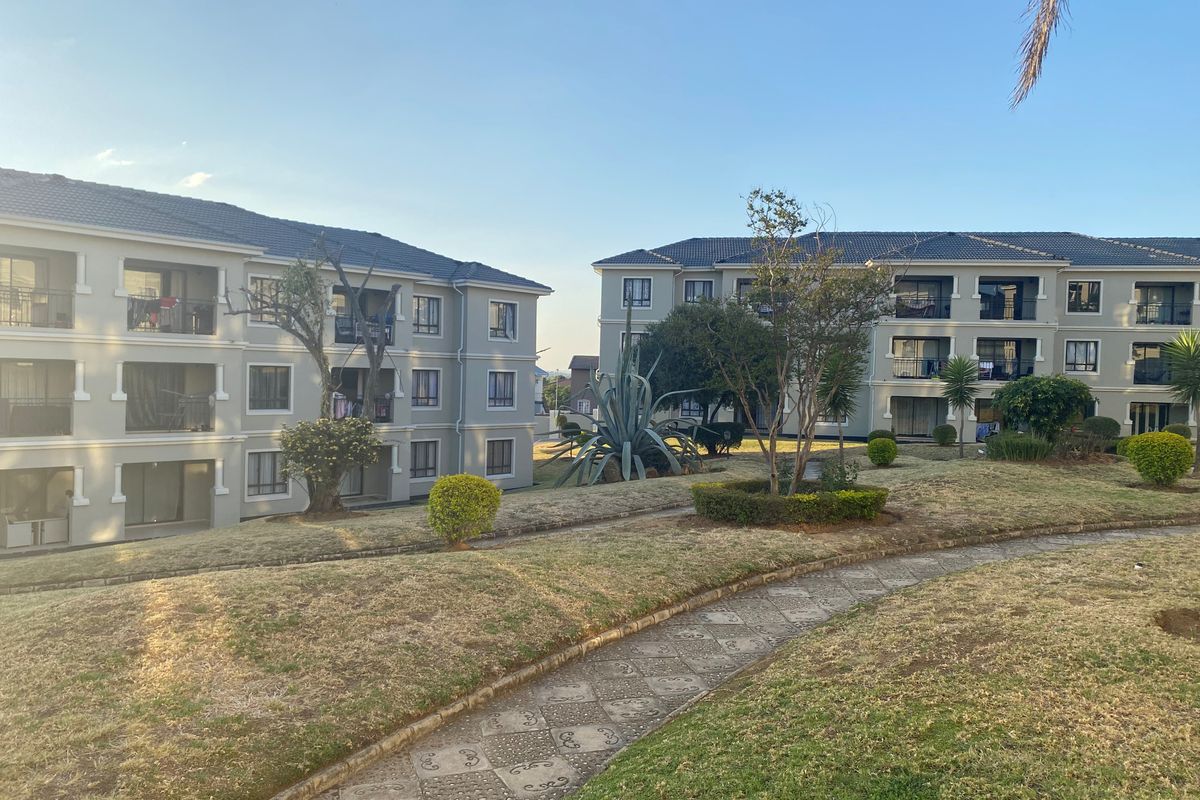 Exterior view of apartment complex buildings featuring landscaped grounds, paved walkways, and private balconies.