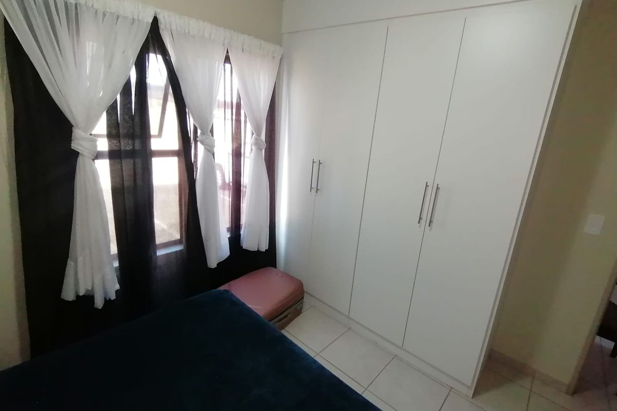 A bedroom featuring white built-in wardrobes and tiled flooring, providing functional storage space.