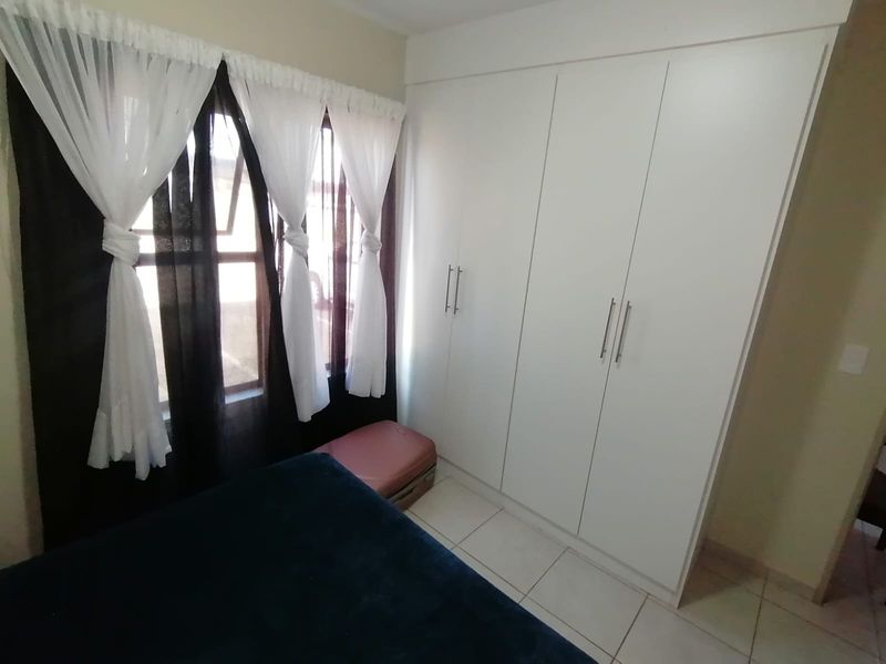 A bedroom featuring white built-in wardrobes and tiled flooring, providing functional storage space.