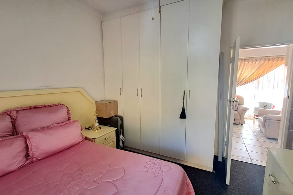 A bedroom featuring white built-in cupboards and direct access to an adjacent living area.
