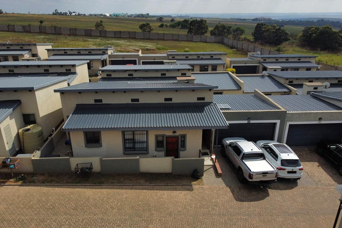 Aerial view of a residential complex featuring modern single-story units with corrugated metal roofs, paved driveways, and attached garages.