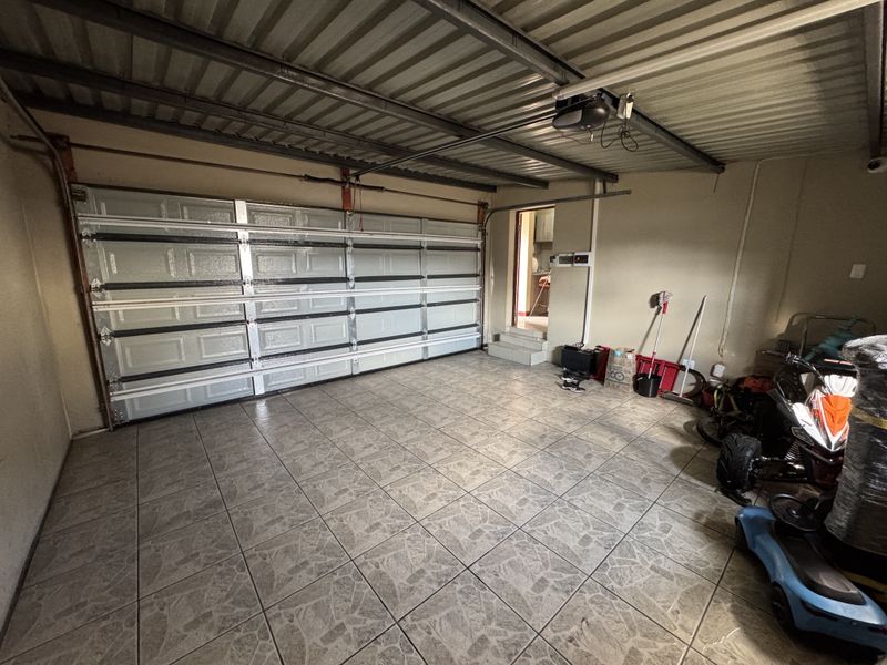 A spacious double garage featuring tiled flooring, a sectional overhead garage door, and direct internal access to the home.
