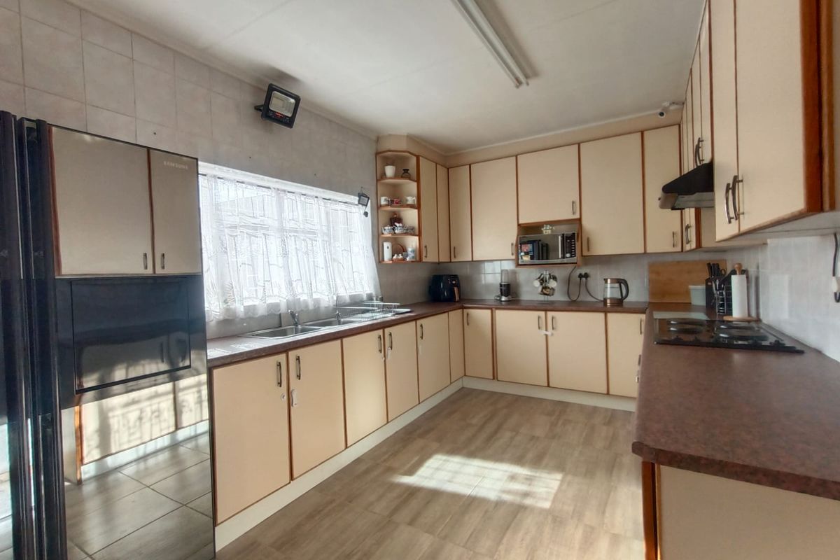 A functional kitchen featuring ample cabinetry, laminate countertops, a built-in hob, and an extractor fan, offering a practical layout for daily meal preparation.