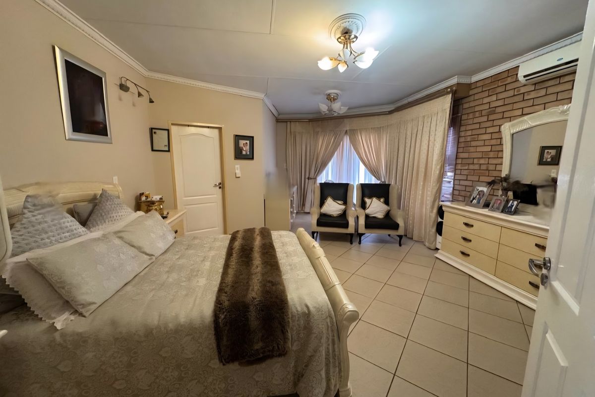 Spacious bedroom featuring tiled flooring, a decorative brick feature wall, and a wall-mounted air conditioning unit.