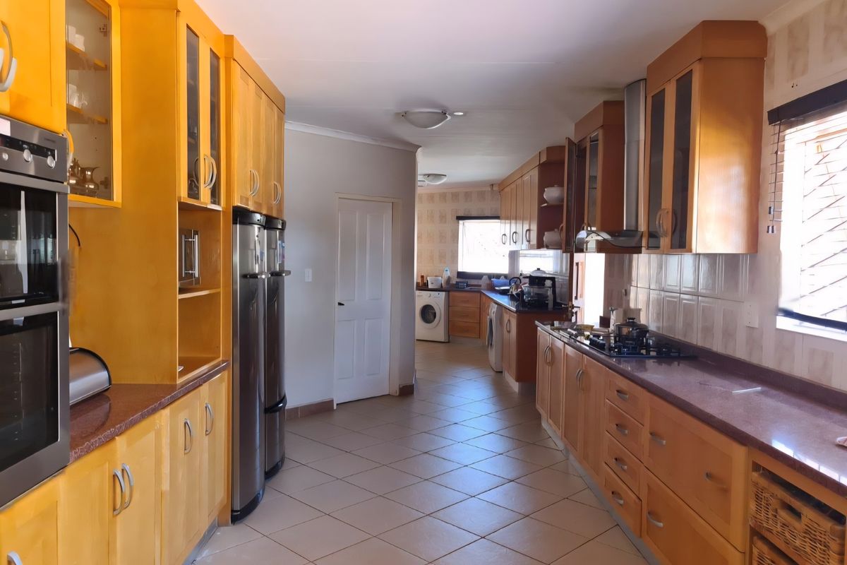 Spacious kitchen featuring extensive wooden cabinetry, granite countertops, integrated oven, and a separate laundry area with tiled flooring throughout.