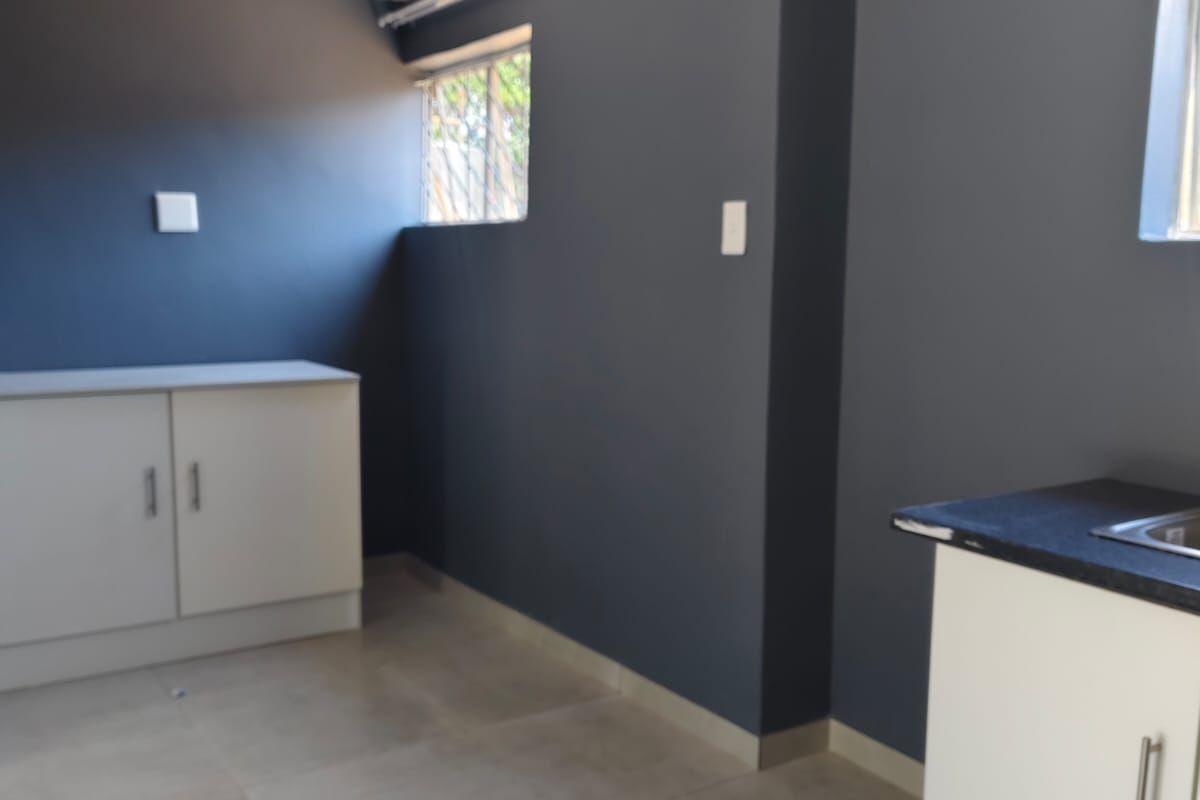 A clean, functional scullery area featuring built-in cabinetry, a sink, tiled flooring, and a modern tongue and groove ceiling finish.