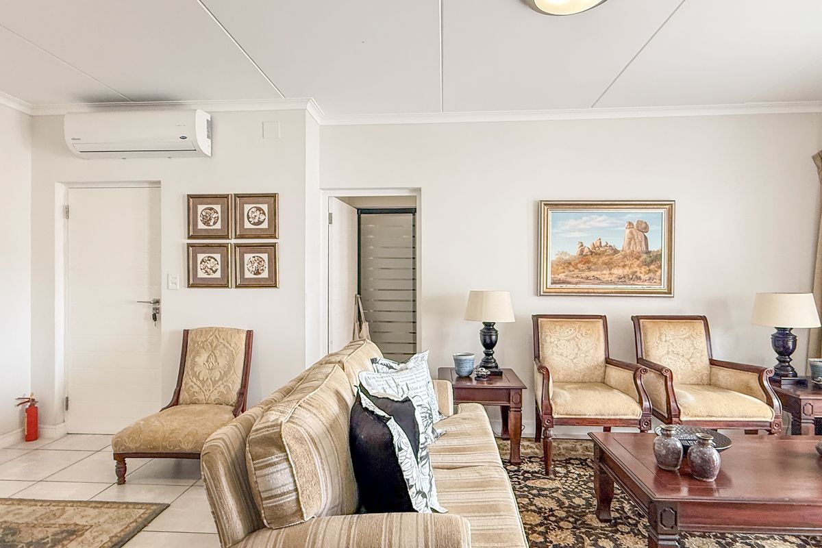 A comfortable living room featuring tiled flooring, a wall-mounted air conditioning unit, and neutral wall finishes.