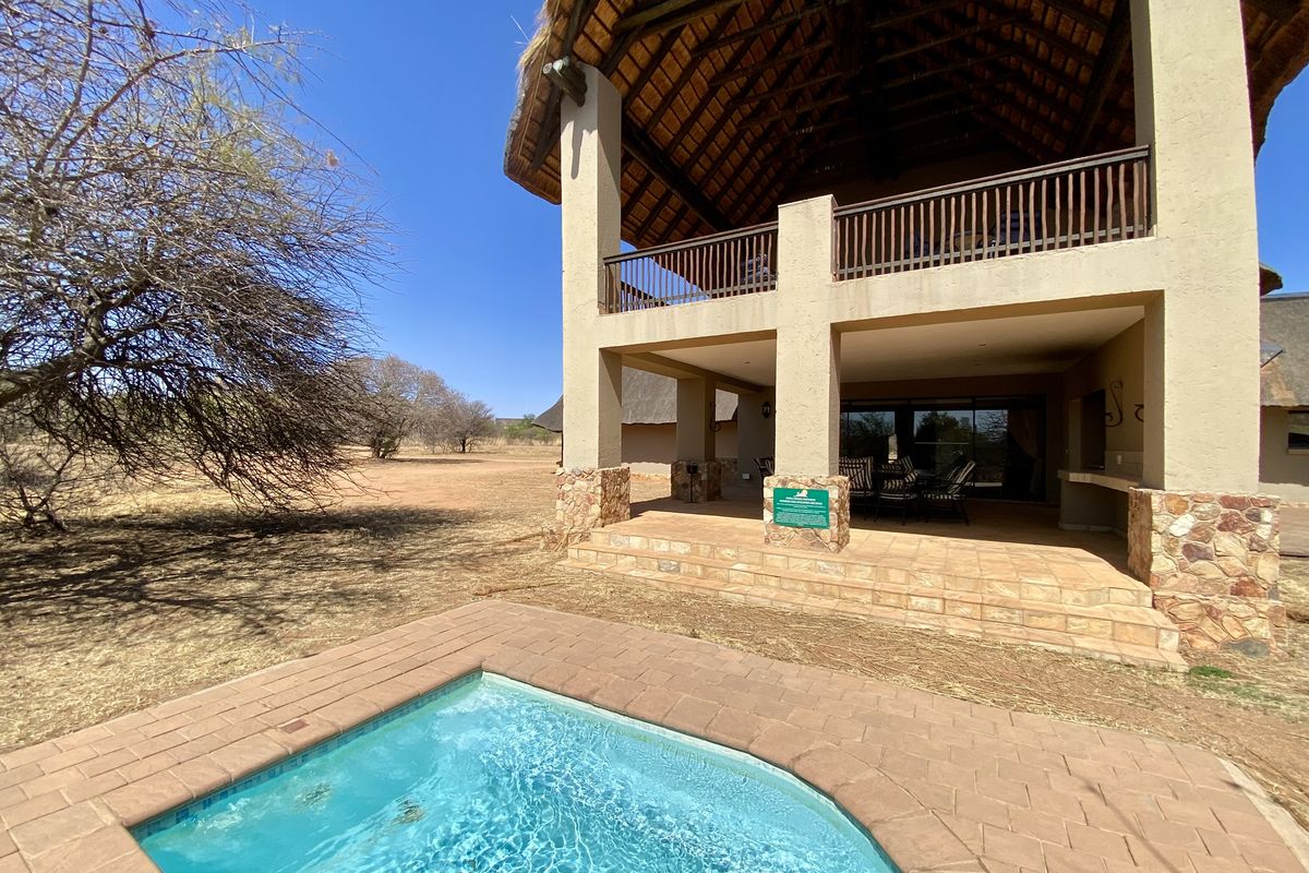 A spacious double-story thatched home featuring a covered patio, built-in braai area, and a private plunge pool set in a natural bushveld landscape.