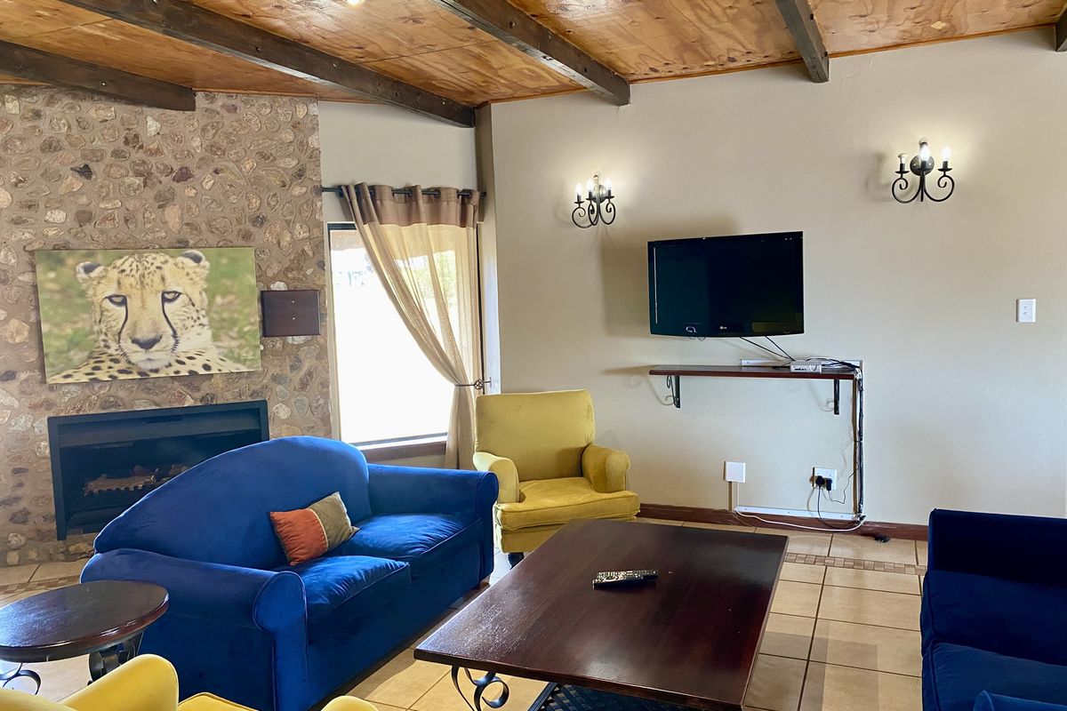 Living room featuring a stone-clad fireplace, exposed timber beam ceiling, and tiled flooring, creating a rustic atmosphere.