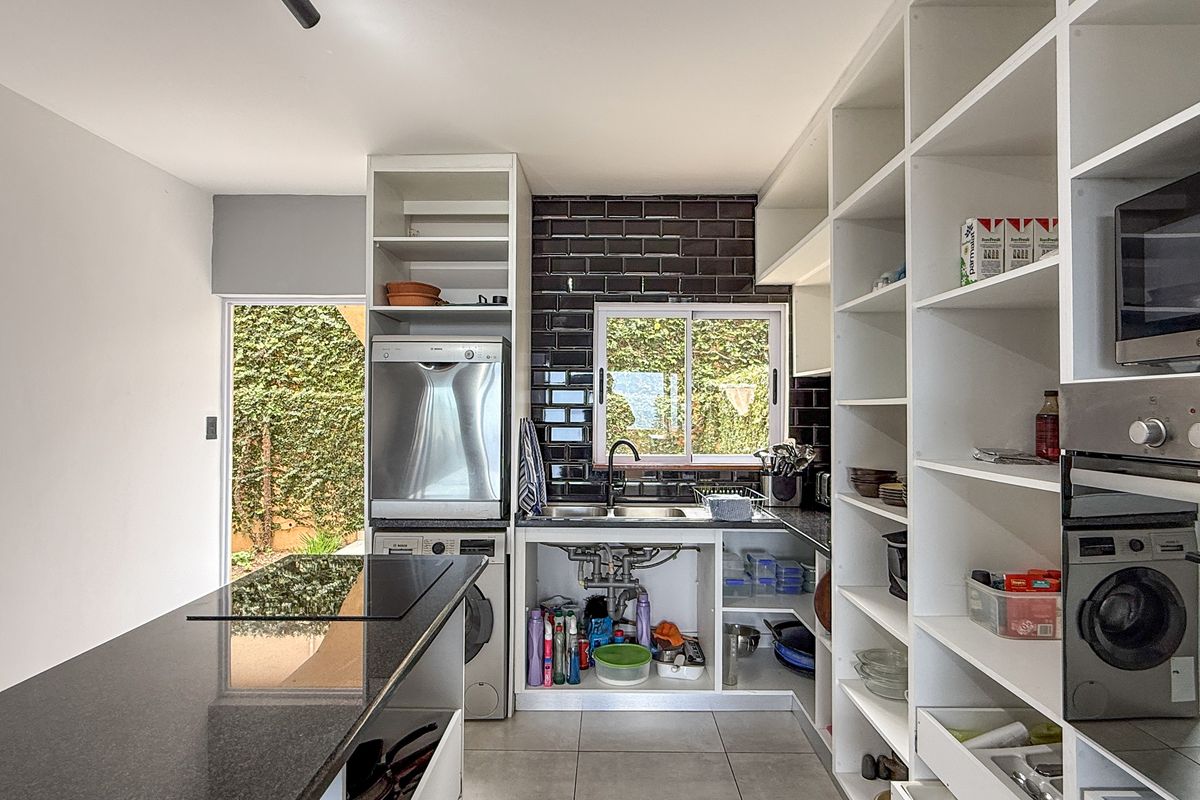 Functional kitchen featuring dark subway tile backsplash, granite countertops, built-in oven, microwave, and extensive open shelving for storage.