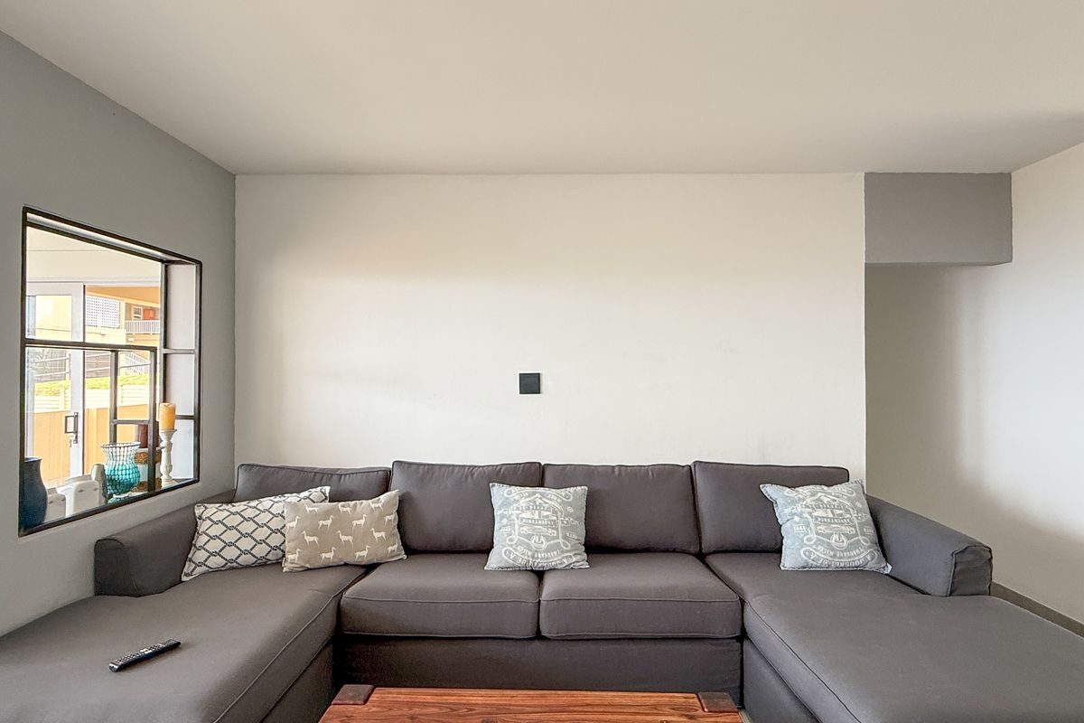 A living room featuring a large grey sectional sofa, a window with a view, and neutral wall finishes.
