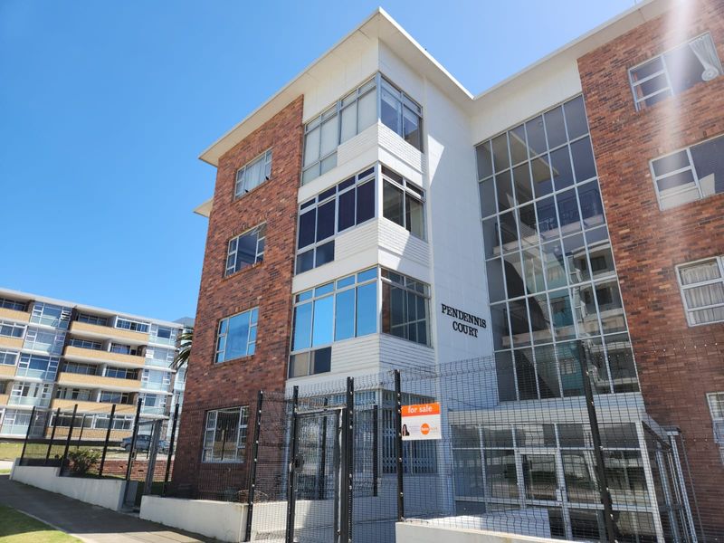 Exterior view of Pendennis Court apartment building featuring a brick and glass facade with secure perimeter fencing and gated entrance.
