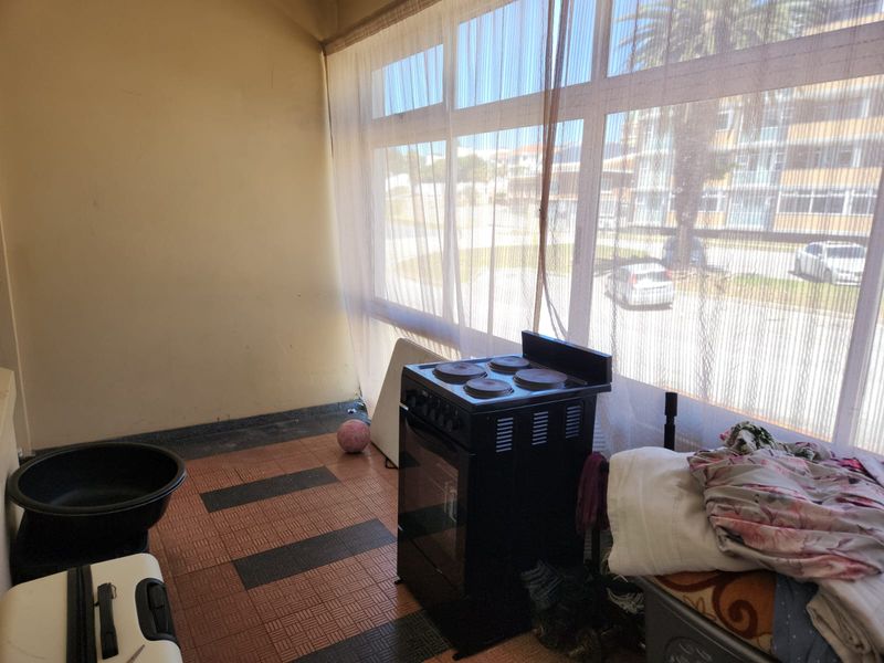 Enclosed balcony area featuring large windows and tiled flooring, offering a versatile space with potential for modernization.