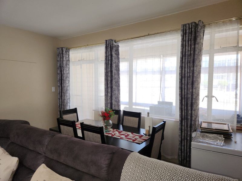 A living area featuring a large window with curtain rods, providing natural light to the space.